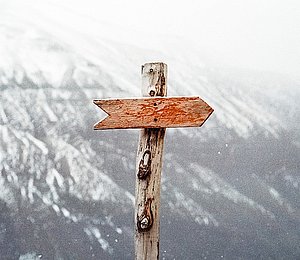Photo: Wooden signpost without imprint in front of mountain scenery