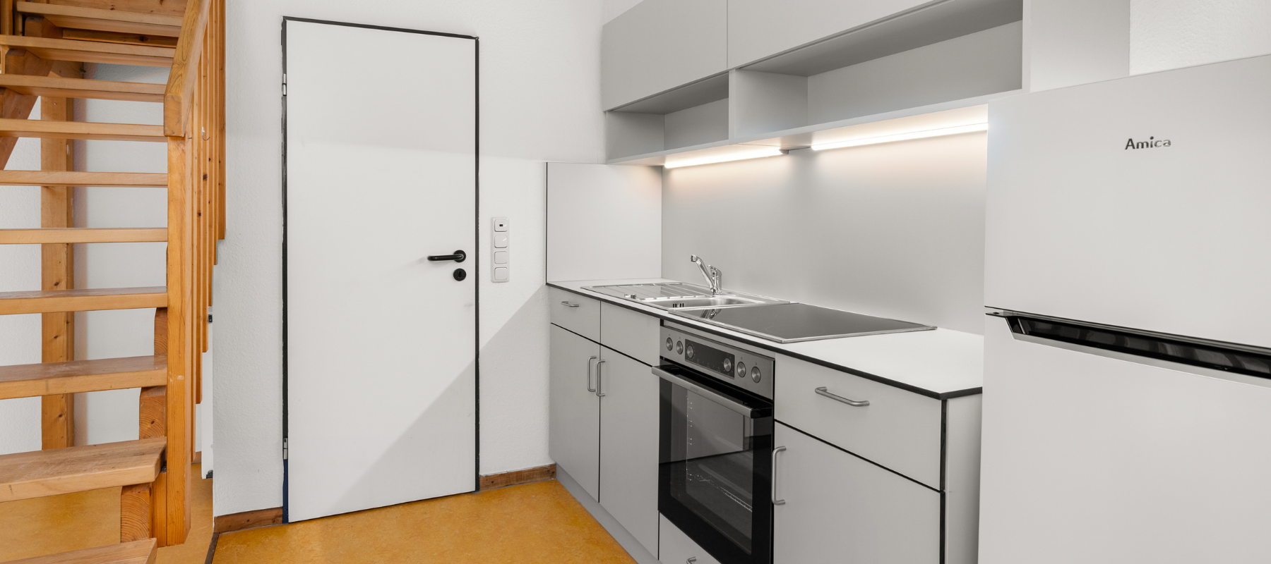 Foto von der Küchenzeile der Studiowohnung. Daneben sieht man die Türe zum Bad.