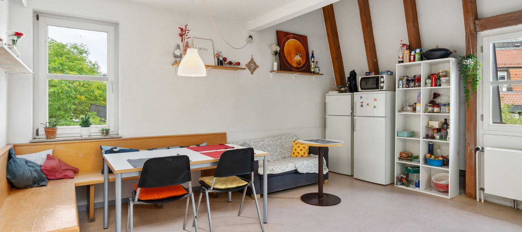 Gemeinschaftsküche in WG mit Eckbank, Sofa, Kühlschränken und Vorratsregalen.