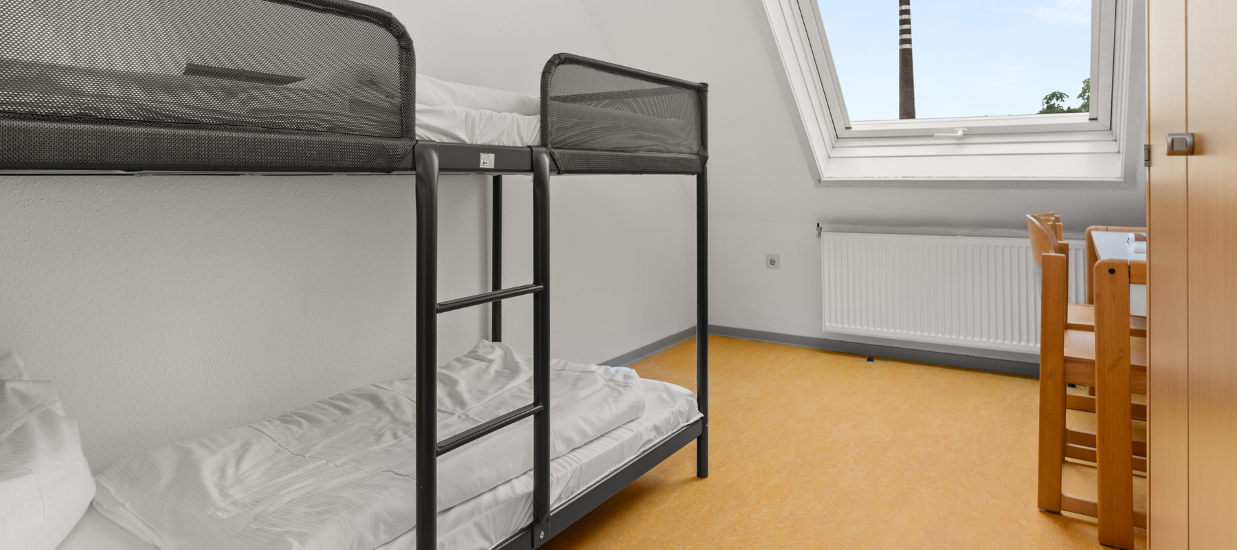 Foto des Familienzimmers. Zu sehen ist das Kinderzimmer mit Doppelstockbett. Daneben eine Schräge mit Fenster..