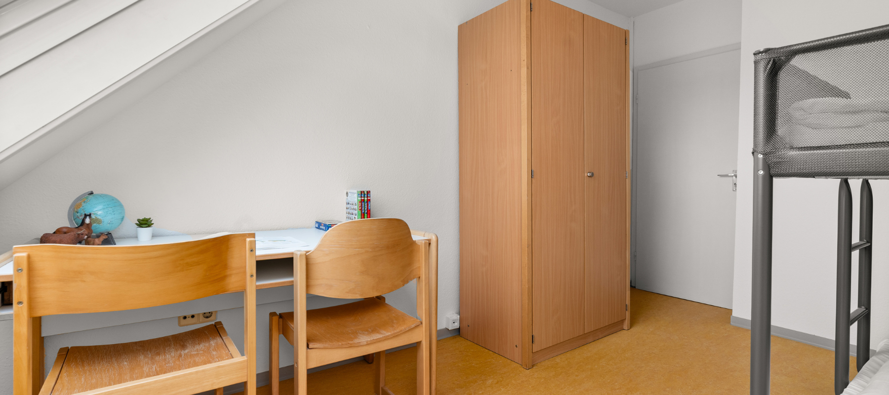 Foto des Familienzimmers. Zu sehen ist das Kinderzimmer mit Doppelstockbett, Schreibtisch mit zwei Stühlen und ein Kleiderschrank.
