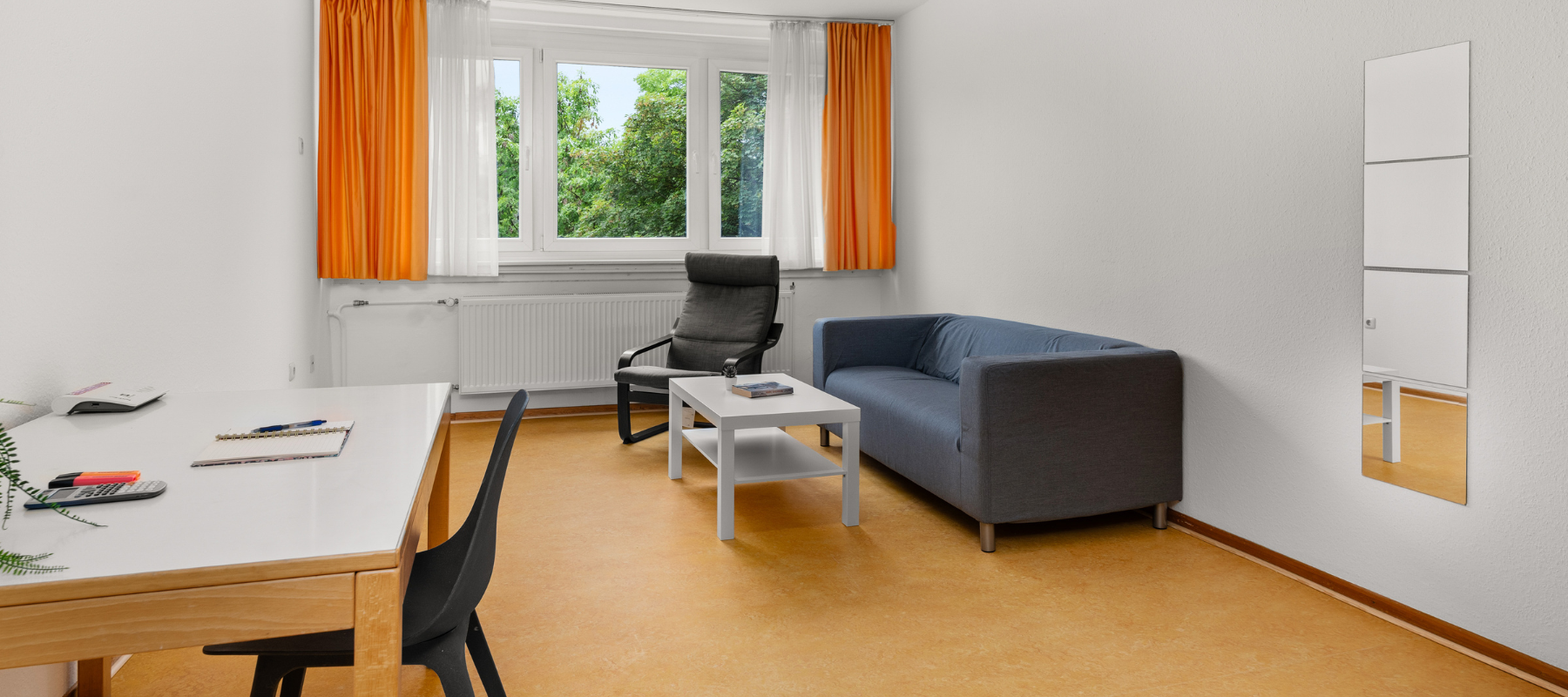 Foto des Familienzimmers. Zu sehen ist das Wohnzimmer mit Sofa und Schreibtisch.