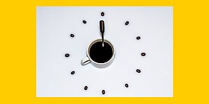Symbol-Grafik: Weisses Zifferblatt einer Uhr vor gelbem Hintergrund, volle Kaffeetasse in der Mitte, Henkel und Kaffeeloeffel als Zeiger auf 8 Uhr